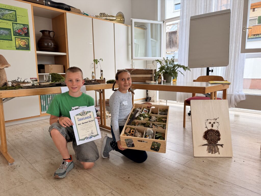 Emma-Madlen Nestel und Tom Fink aus der Klasse 5a haben am 08.07.2026 beim schulübergreifenden Naturforscherwettbewerb der Haug-Taxis-Stiftung im Gemeindehaus Sonne in Kleinaspach den 1. Platz erreicht. Mit ihrer hervorragend vorbereiteten gemeinsamen Präsentation setzten sie sich gegen vier weitere Schulen durch.